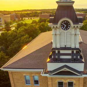 Gustavus clock tower with campus in the background at sunset.